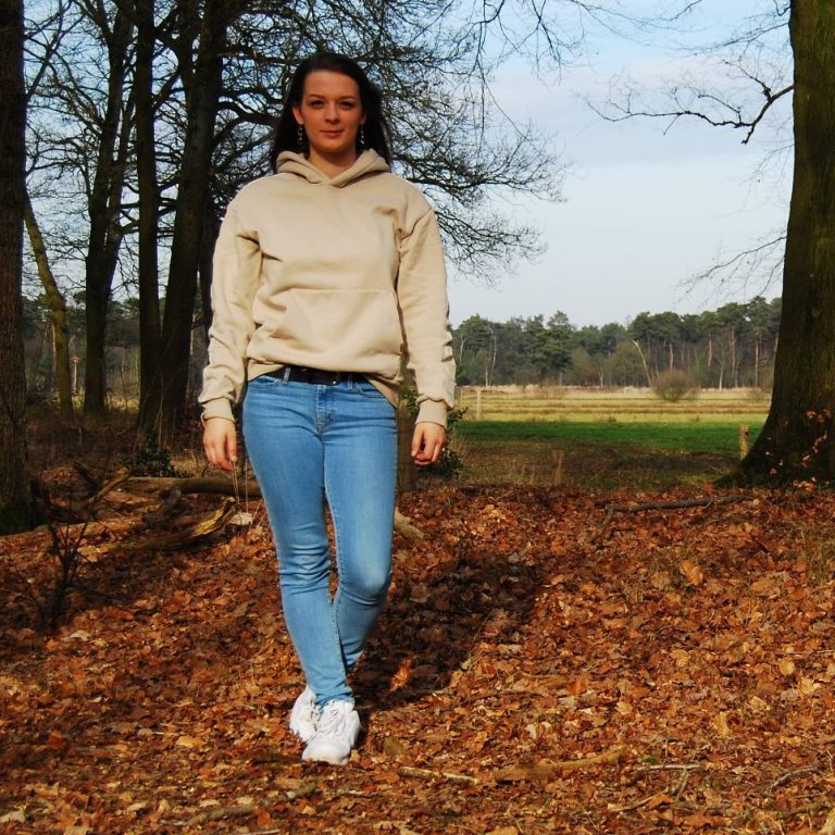 Vrouwelijke therapeut in het bos met op de achtergrond een open vlakte.